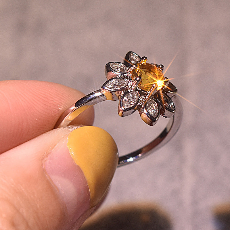 Velora diamond studded sunflower ring with yellow center stone held by hand with yellow nail polish
