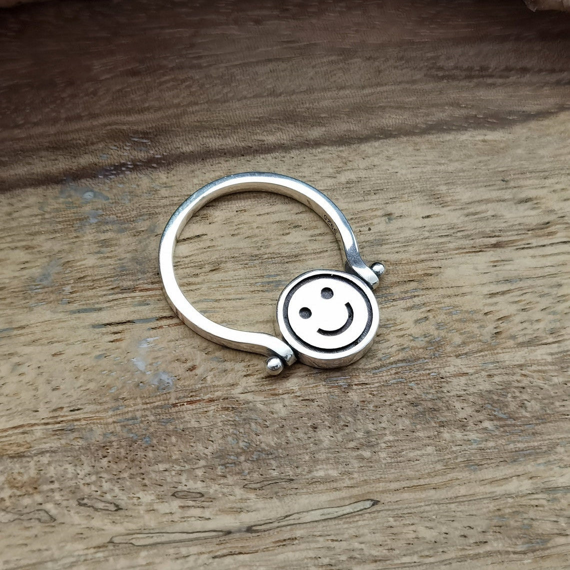 Velora Ring silver smiley face spinner ring with smooth band on wooden surface