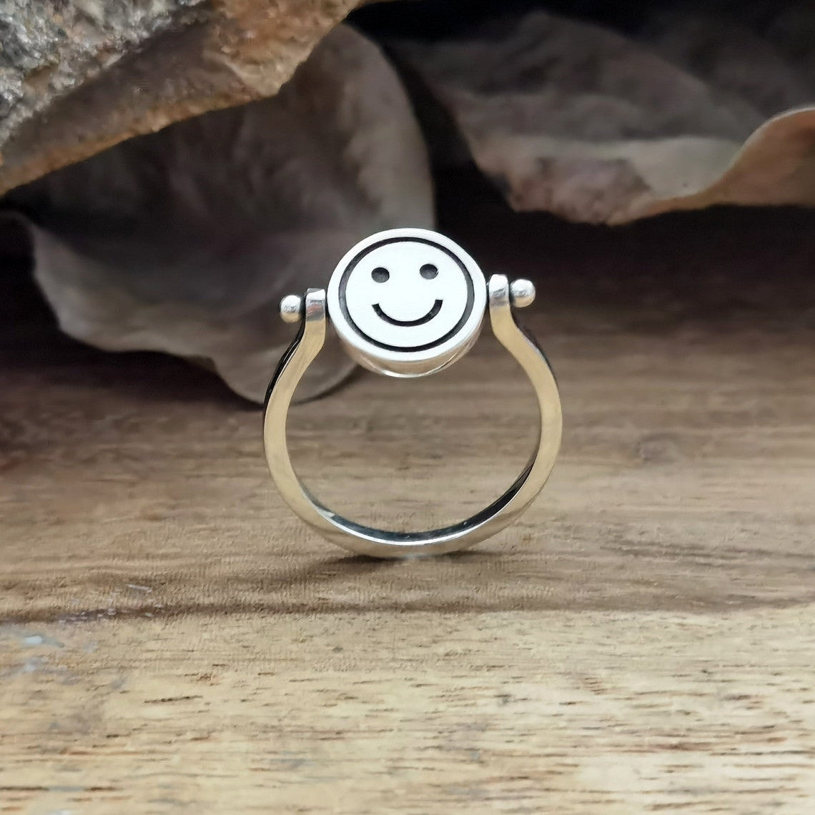 Velora Ring silver smiley face spinner ring with rotating smiley face design on wooden surface