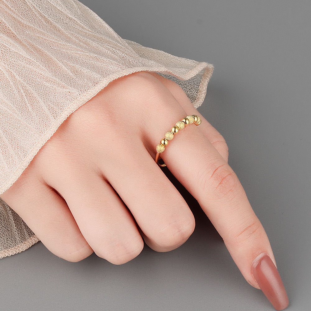 Velora Ring worn on finger featuring a frosted rotation ring design with gold bead details